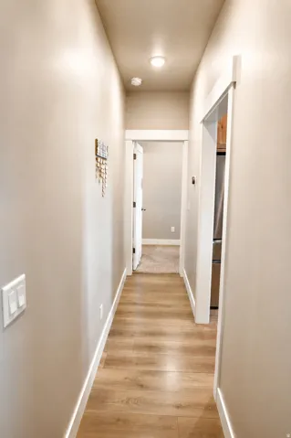 Hallway featuring wood-finish flooring, recessed lighting, and white trim
