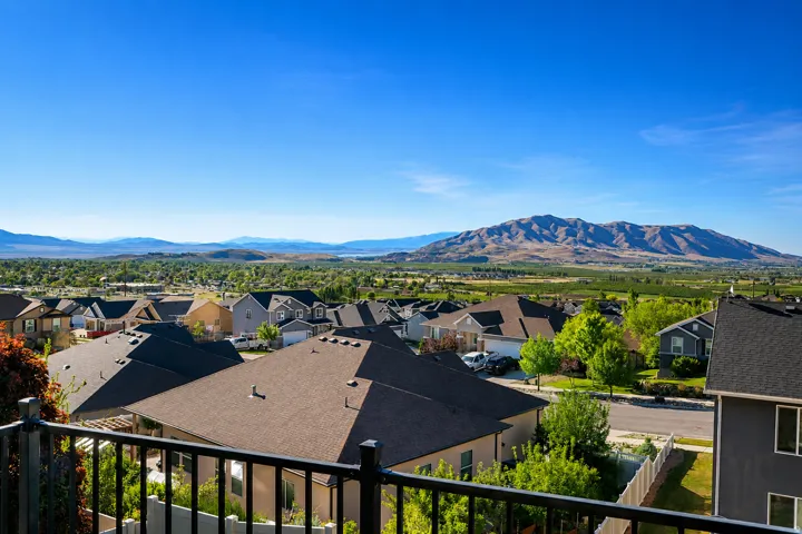 Panoramic mountain scenery frames a residential area featuring numerous homes with gabled roofs and surrounding foliage