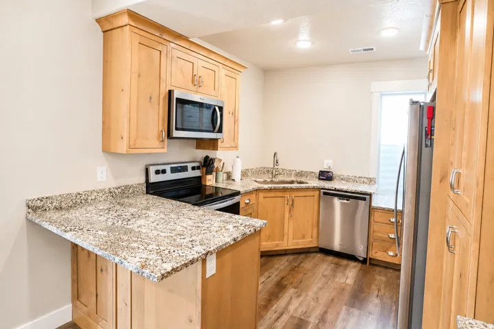 Kitchen featuring wood-finish flooring, light wood cabinetry, and granite countertops