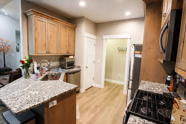 Kitchen featuring wood-finish cabinetry, granite countertops, and stainless steel appliances including a gas range and microwave