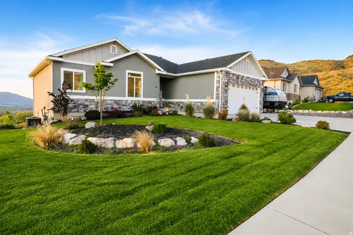 Contemporary gray stucco exterior with stone veneer accents, a two-car garage, and a concrete driveway