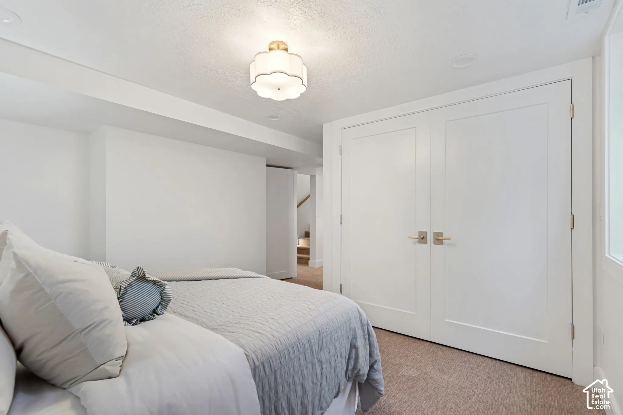 Carpeted room featuring a ceiling-mounted light fixture, white walls, and bi-fold closet doors with brushed nickel hardware