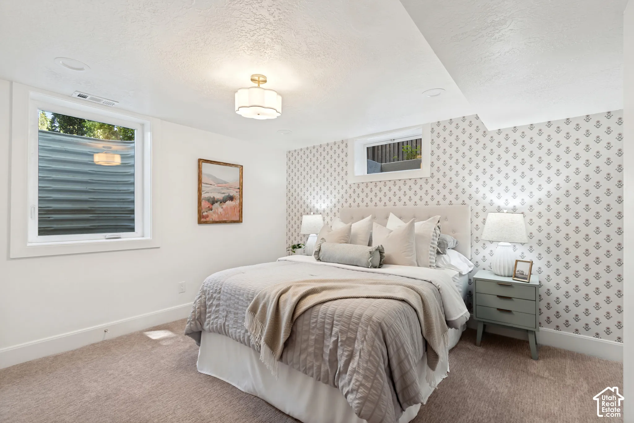 Carpeted room featuring a patterned accent wall, white painted walls, and a window with a white frame