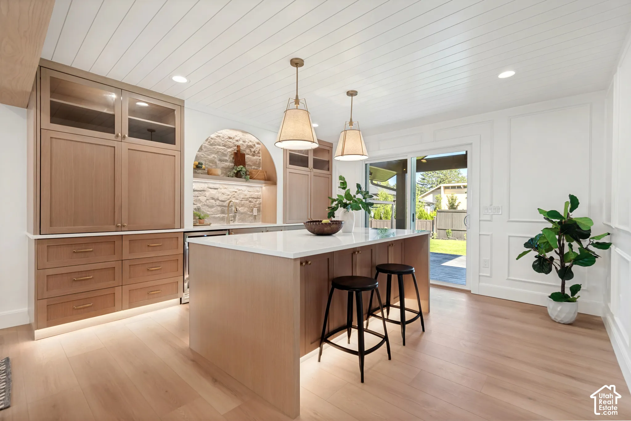 Open-concept kitchen featuring light wood cabinetry and a central island with a white countertop