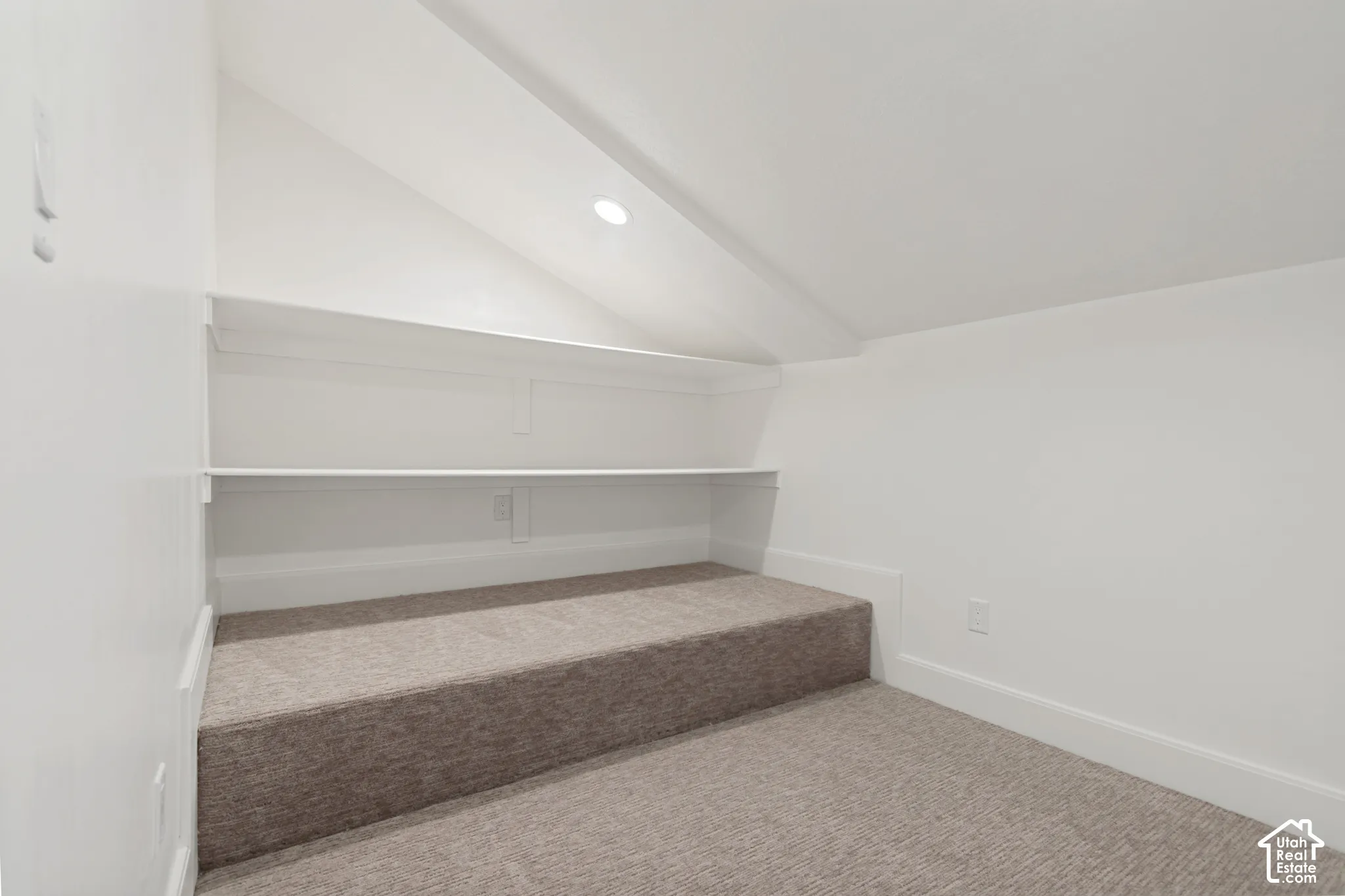 Carpeted alcove featuring built-in shelving, recessed lighting, white baseboards, and a neutral color palette