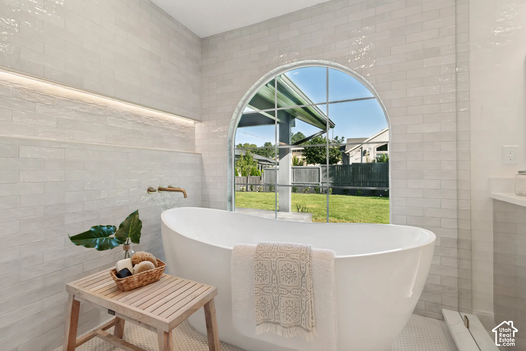 Freestanding soaking tub set against a large arched window