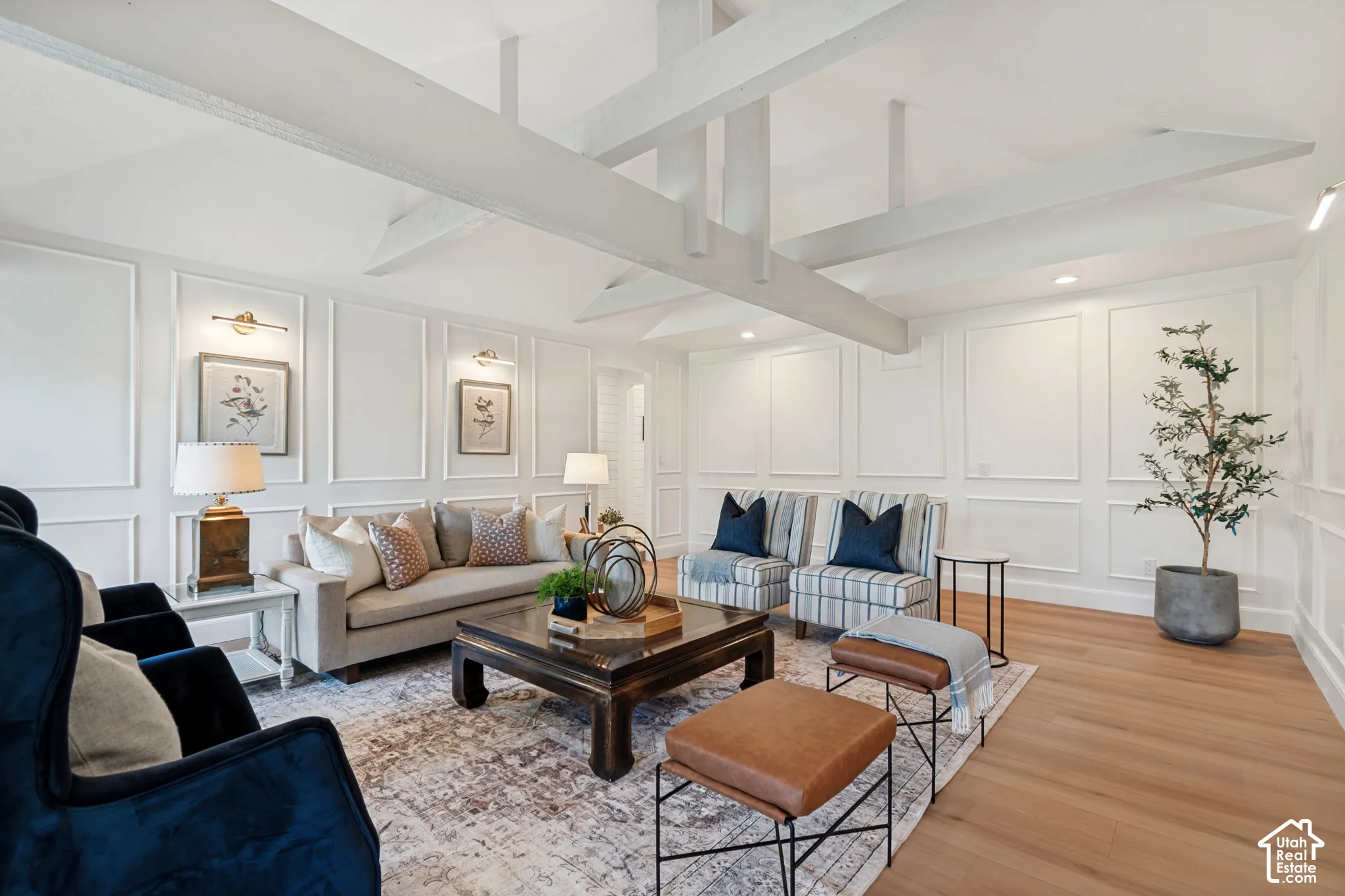 Living area featuring vaulted ceilings with exposed beams, wood-finish flooring, recessed lighting, and decorative wall paneling