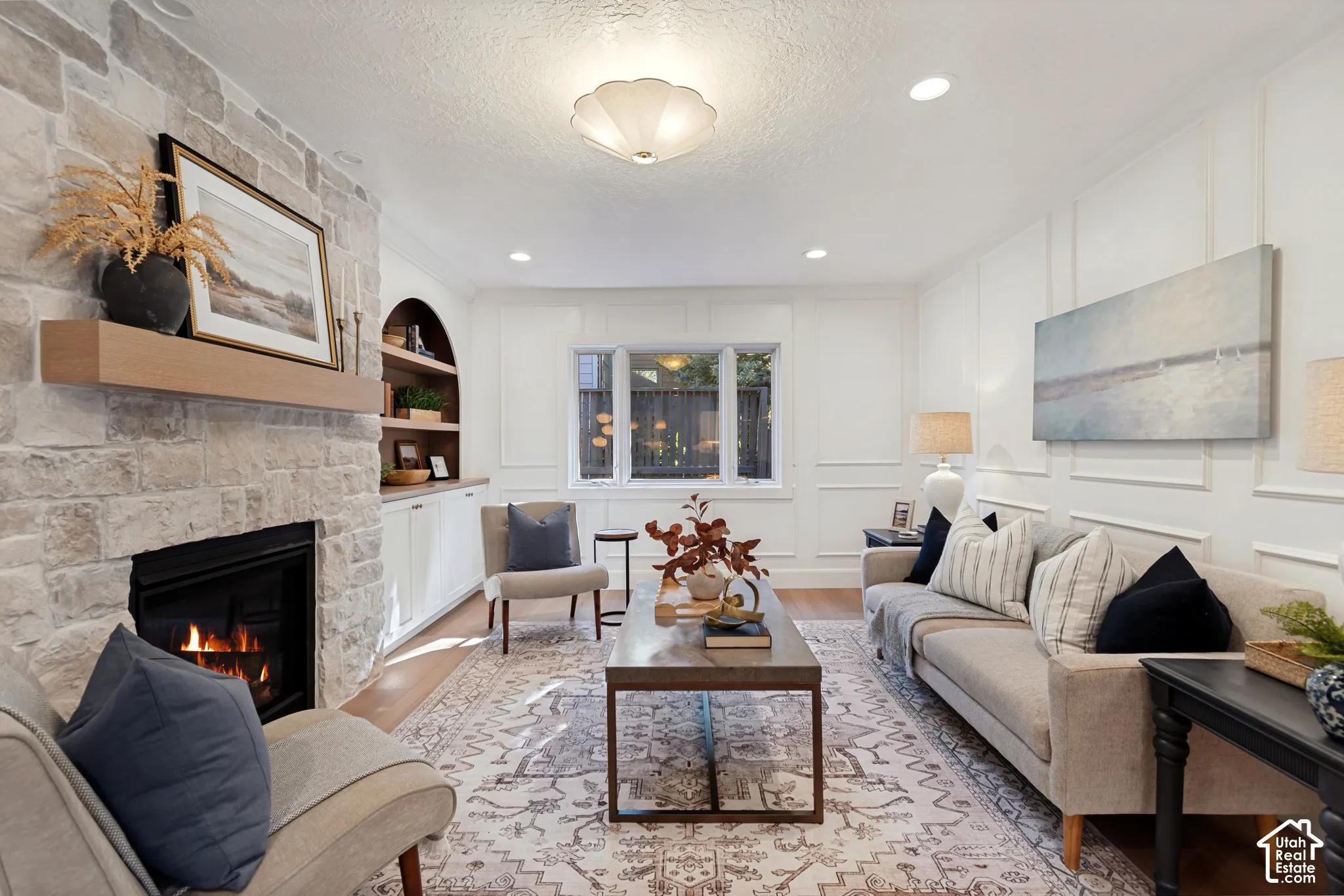 Living area featuring a stone-clad fireplace with a wood mantel, recessed lighting, and wall paneling