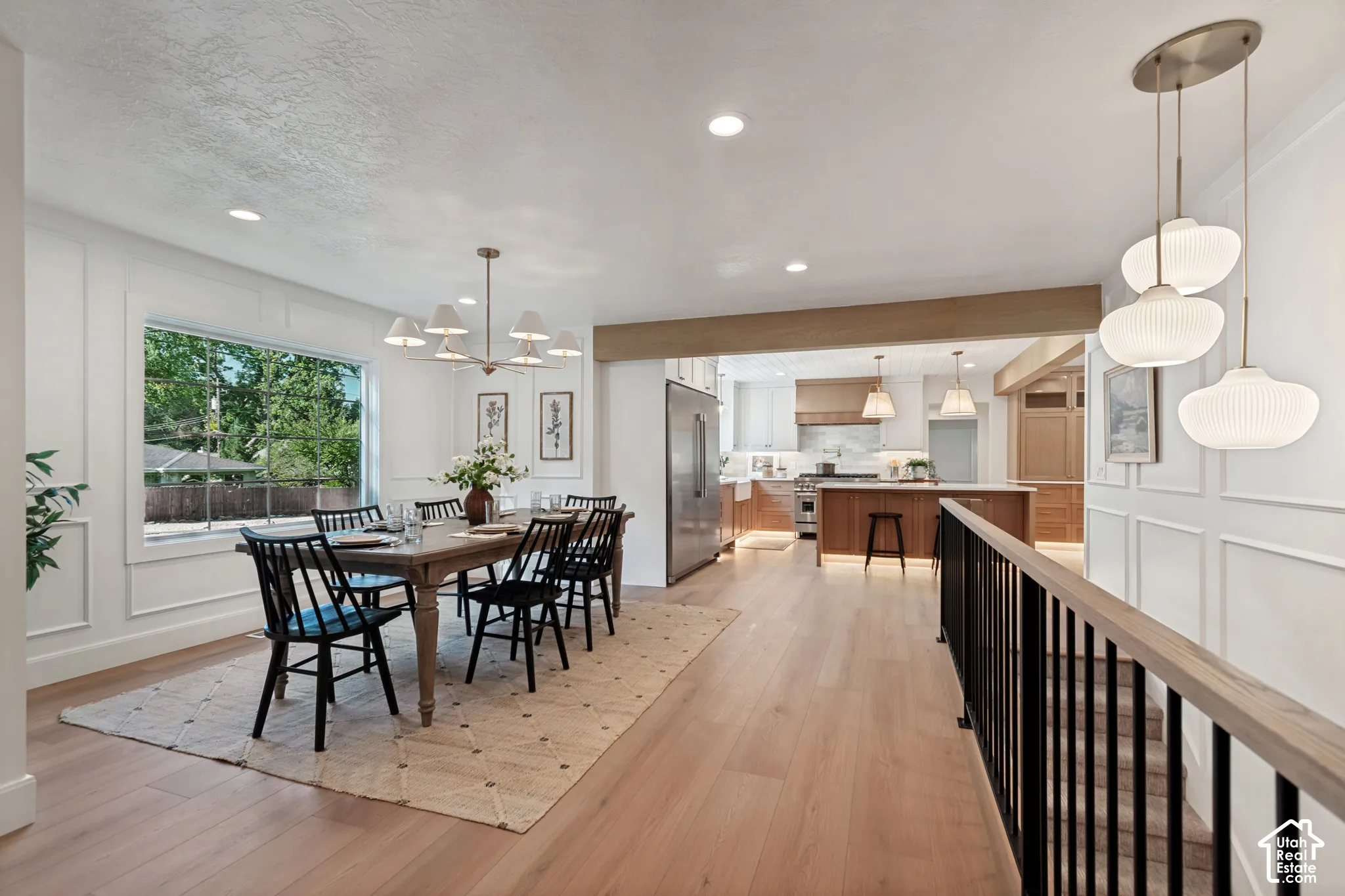 Bright dining area featuring a large picture window, paneling, and wood-finish flooring