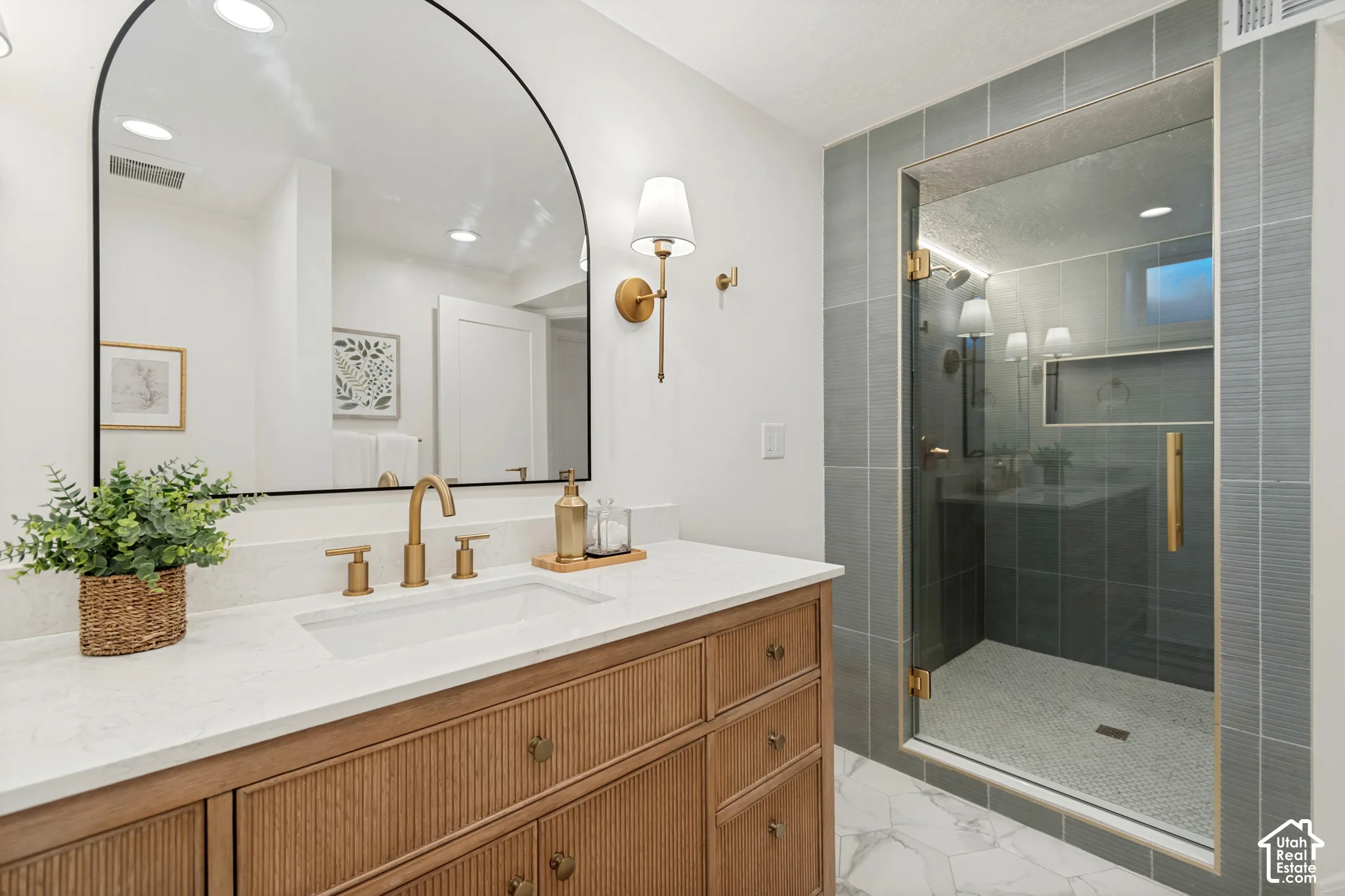Modern bathroom featuring a wood-finish vanity with a white countertop and gold-tone fixtures