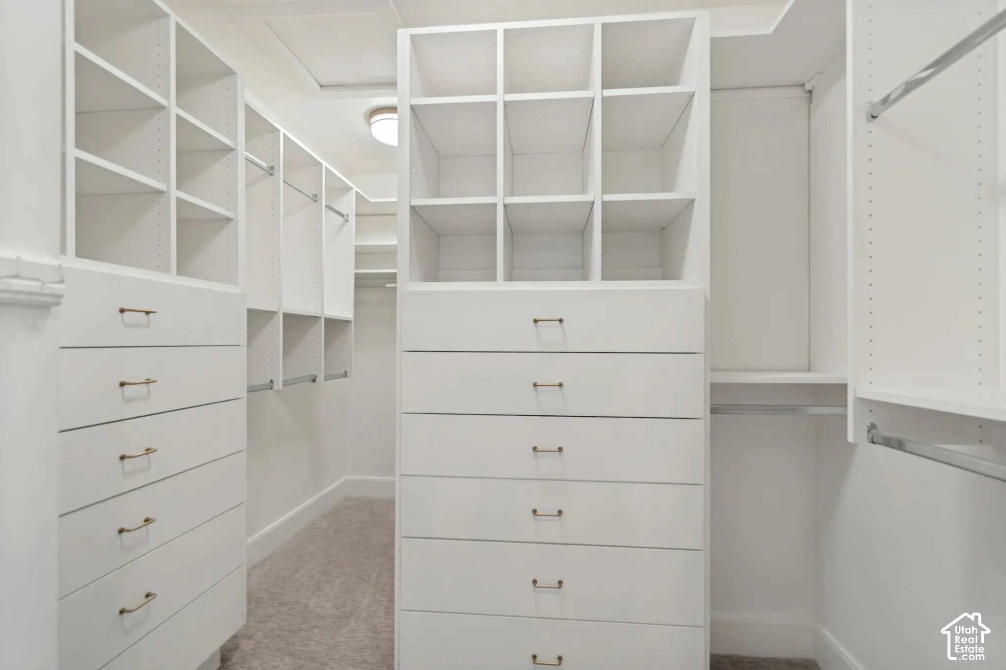 White custom closet system featuring integrated drawers with brass hardware, open shelving, and hanging rods
