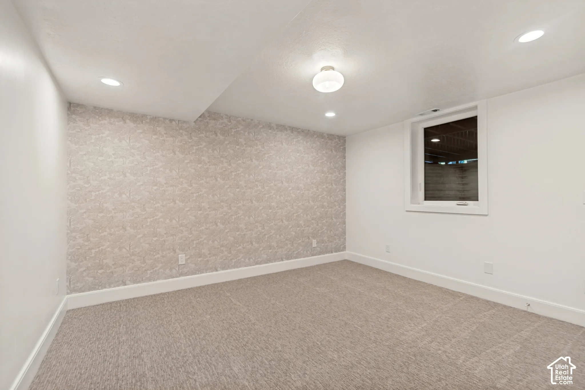 Carpeted room featuring a patterned accent wall, recessed lighting, a flush mount ceiling fixture, and a window with white trim