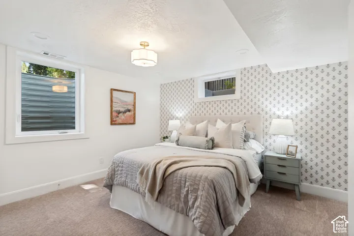 Carpeted room featuring a patterned accent wall, white painted walls, and a window with a white frame