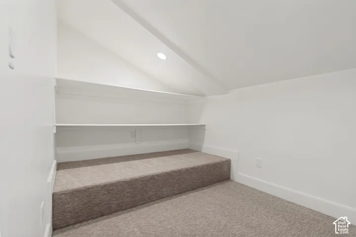 Carpeted alcove featuring built-in shelving, recessed lighting, white baseboards, and a neutral color palette