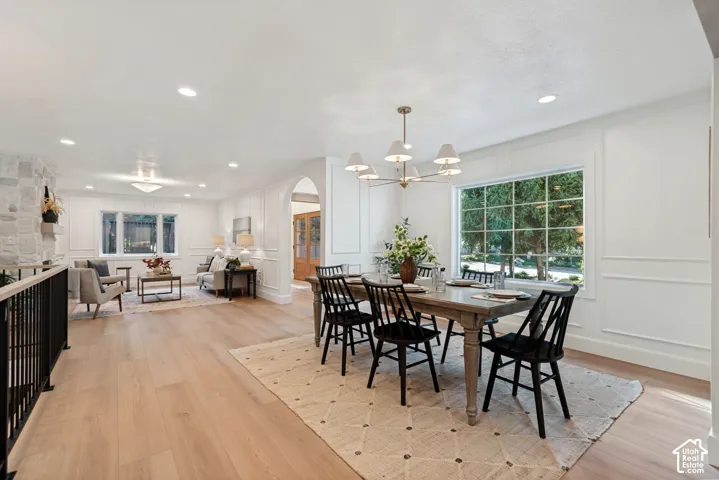 Open-concept dining and living areas featuring light wood-finish flooring, recessed lighting, and white paneled walls