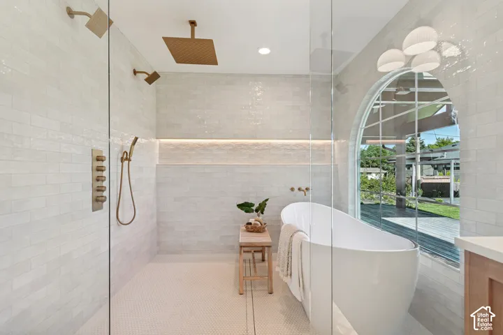 Freestanding soaking tub positioned by an arched window overlooking exterior decking and lawn