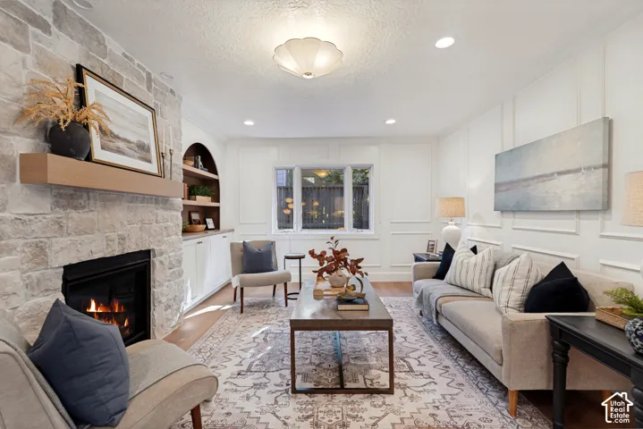 Living area featuring a stone-clad fireplace with a wood mantel, recessed lighting, and wall paneling