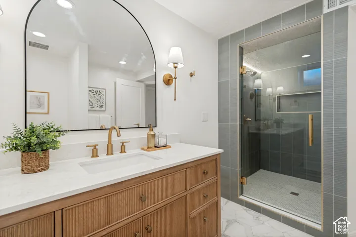 Modern bathroom featuring a wood-finish vanity with a white countertop and gold-tone fixtures