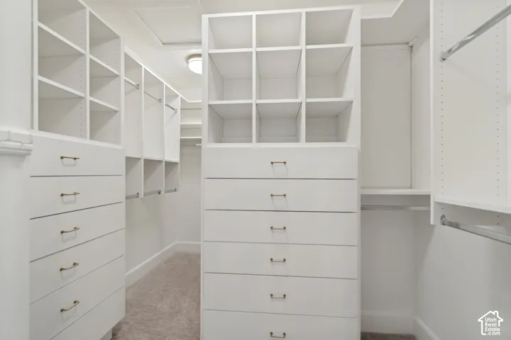 White custom closet system featuring integrated drawers with brass hardware, open shelving, and hanging rods