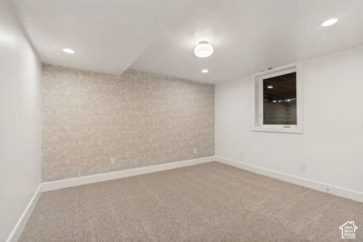 Carpeted room featuring a patterned accent wall, recessed lighting, a flush mount ceiling fixture, and a window with white trim