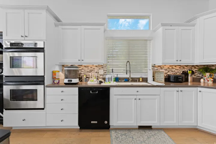 Kitchen featuring white cabinetry with crown molding, a stainless steel double oven, and a built-in dishwasher