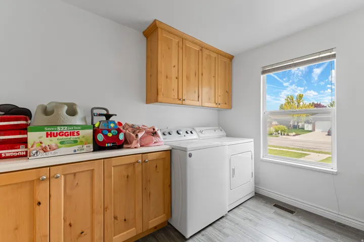 Dedicated laundry area featuring wood cabinetry, a light-colored countertop, and a window providing natural illumination