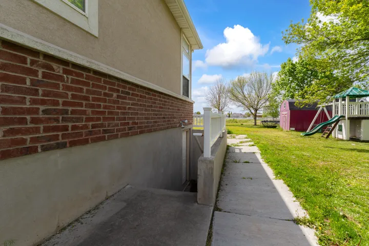 Exterior side of the property featuring a brick and stucco facade, a concrete walkway, and a fenced area
