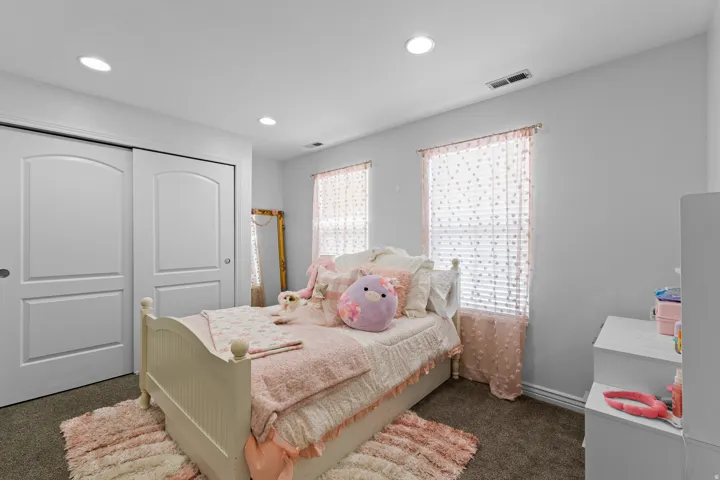 Recessed lighting illuminates this room featuring two windows with blinds, a sliding double-door closet, and neutral wall tones