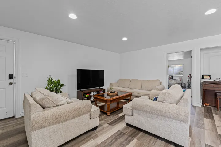 Spacious interior featuring wood-finish flooring, recessed lighting, and a white paneled door with contemporary hardware