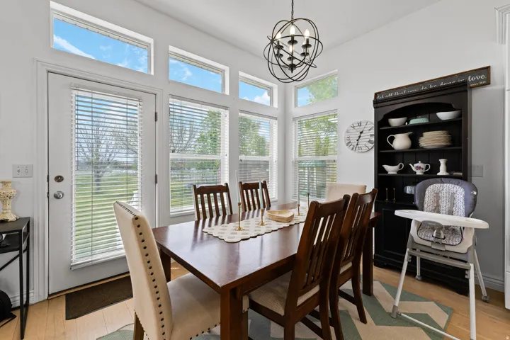Dining area with wood-finish flooring, a contemporary black orb chandelier, and ample natural light from multiple windows