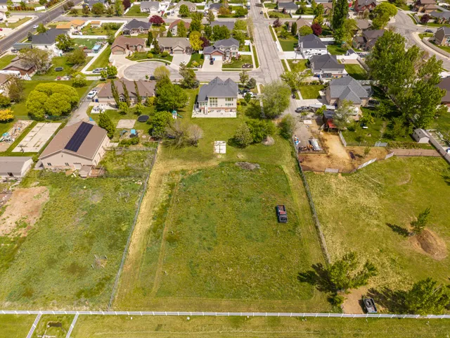 Expansive green lot featuring a partially fenced perimeter and surrounding residential properties