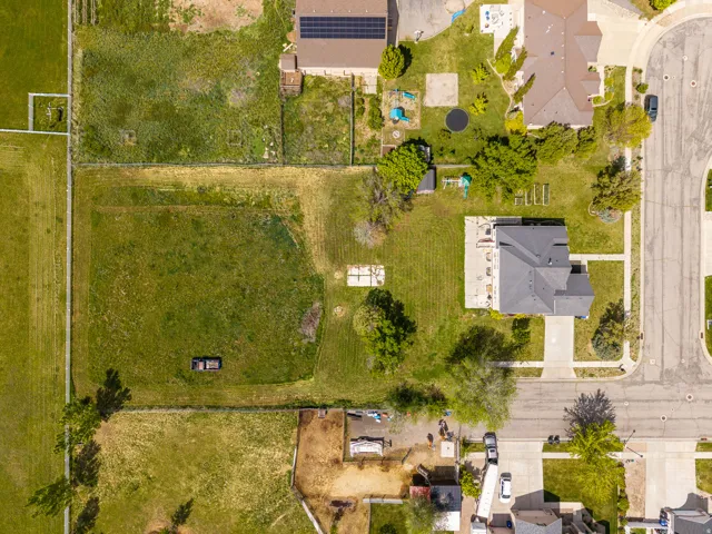 Expansive lot featuring a residential structure with a dark-pitched roof, a paved driveway, and established green landscaping