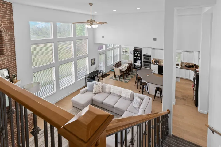 Two-story living area featuring a vaulted ceiling and a prominent wall of grid-patterned windows