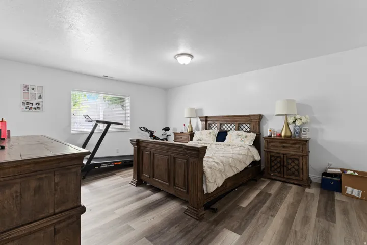 Spacious room featuring wood-finish flooring, a single window with blinds, and white walls