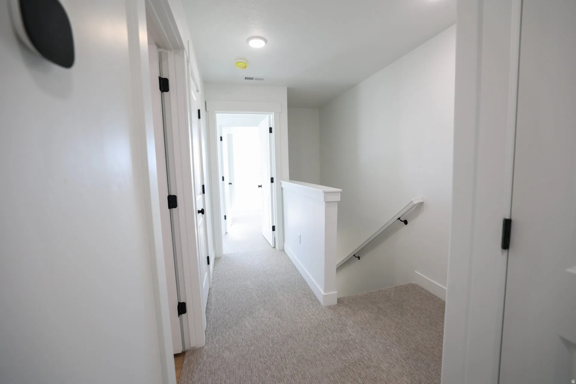 Bright hallway featuring light-colored carpeting and white walls