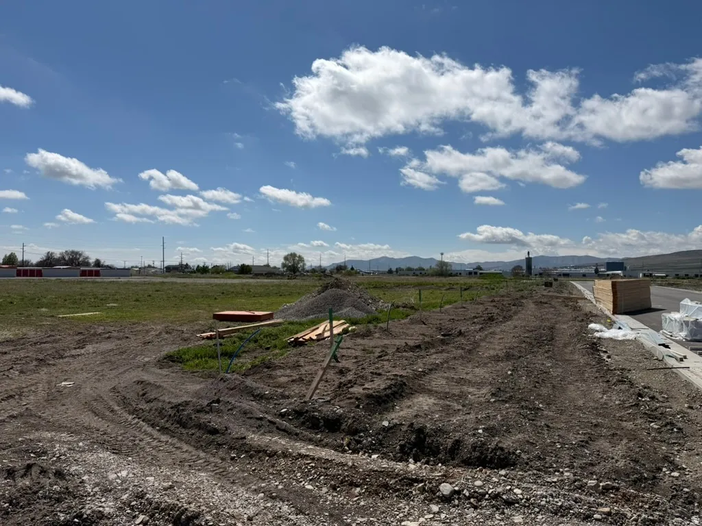 Expansive undeveloped land featuring a cleared building site, existing infrastructure elements, and a distant mountain range backdrop