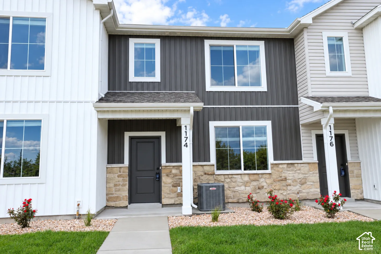 Multi-level exterior featuring a combination of vertical board-and-batten siding and natural stone veneer, double-pane windows, and a concrete walkway