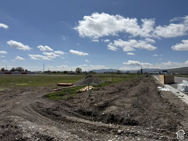 Expansive undeveloped land featuring a cleared building site, existing infrastructure elements, and a distant mountain range backdrop