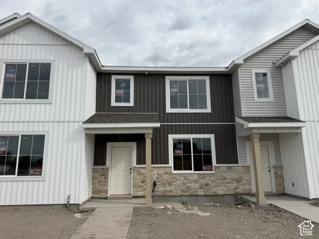 Multi-level exterior featuring vertical siding, horizontal siding, stone veneer accents, and a covered entryway