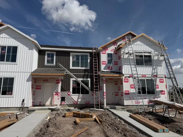 New construction townhome units featuring a contemporary facade, vertical siding, and a gabled roofline