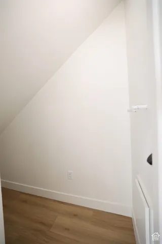 Under-stair storage area with wood-finish flooring, white baseboards, and a white wall finish