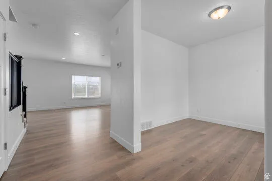 Open-concept interior featuring wood-finish flooring, white baseboards, and a contemporary flush-mount ceiling light