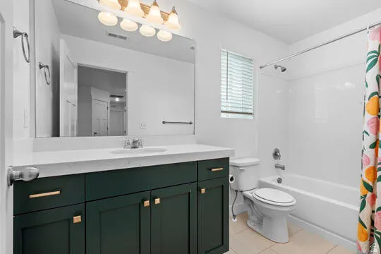 Bathroom featuring a vanity with dark green cabinetry and gold hardware, a white countertop, and a large mirror