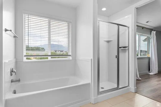 Full bathroom featuring a white tub, chrome fixtures, and a glass-enclosed shower with a built-in shelf