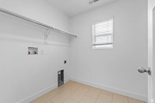 Dedicated laundry room featuring a utility hookup, overhead shelving, and a window with blinds