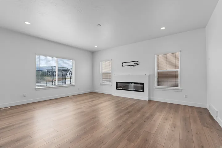 Spacious room featuring wood-finish flooring and multiple large windows