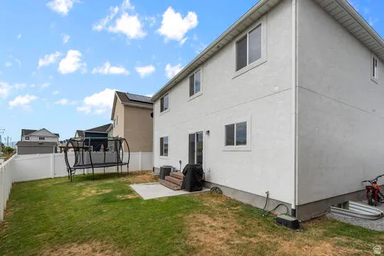 Expansive backyard featuring a manicured lawn, a concrete patio, and a white privacy fence