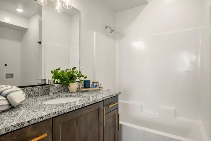 Bathroom featuring a wood-finish vanity with gold-tone hardware, a speckled stone-finish countertop, and an undermount sink