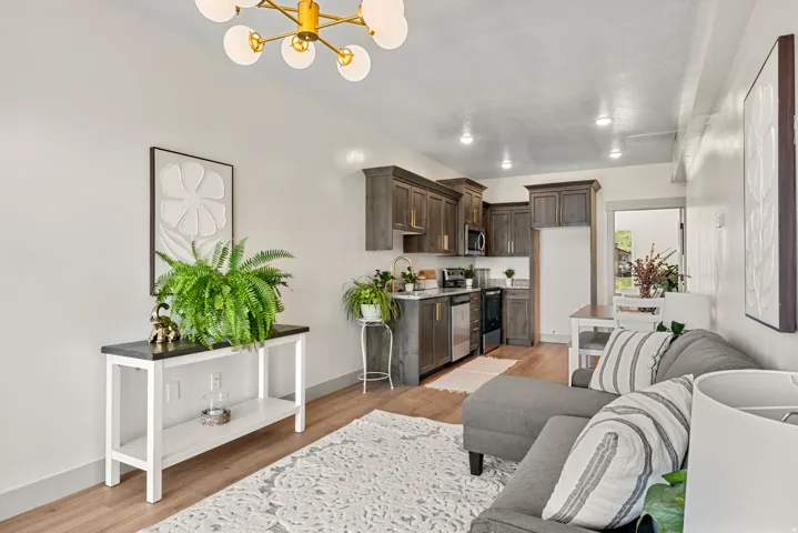 Open-concept living area featuring wood-finish flooring, a contemporary chandelier, recessed lighting, a kitchen with stainless steel appliances, and a dining area with a white table