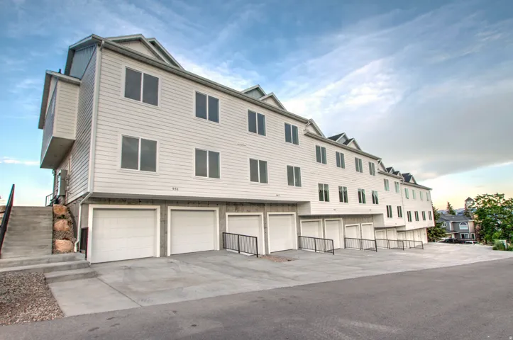 Multi-story townhome-style residences featuring white siding and individual garage access